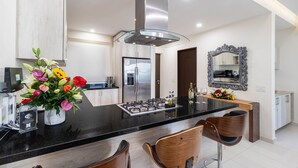 Una cocina moderna con una isla central, electrodomésticos de acero inoxidable y un espejo decorativo.