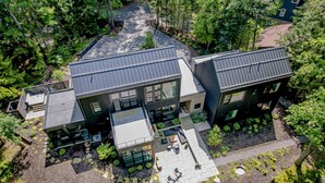 A modern house with a spacious patio, large windows, and a well-maintained garden. - The Birch Bower: Luxury Lakefront Home (Oakland)