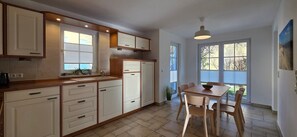 A kitchen with white cabinets, a wooden countertop, and a dining area with a table and chairs.