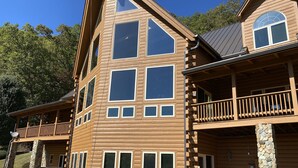 A multi-story wooden cabin with large windows, a balcony, and stone pillars. - Dramatic Remodeled Log home with everything! (Franklin)