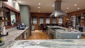 A spacious kitchen with granite countertops, a central island, and wooden cabinetry. - Dramatic Remodeled Log home with everything! (Franklin)