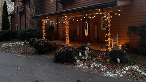 A log cabin with a porch decorated with string lights and Christmas ornaments. - Dramatic Remodeled Log home with everything! (Franklin)
