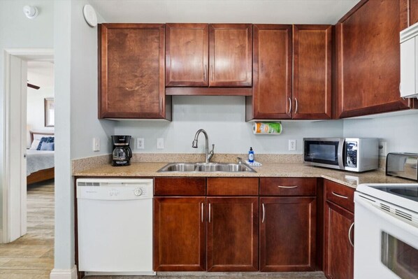A compact kitchen with wooden cabinets, a dishwasher, a microwave, and a toaster.