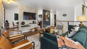 A modern living room with a fireplace, a dining area, and a kitchen visible in the background. - Luxury Living-Kirkland: Stylish Home - Prime Spot! (Kirkland)