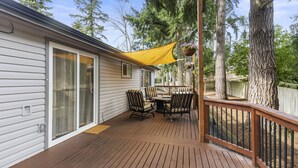 A wooden deck with a table and chairs, a yellow canopy, and hanging flower baskets. - Luxury Living-Kirkland: Stylish Home - Prime Spot! (Kirkland)