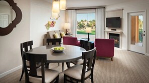 Enjoy a serene view of the golf course from the comfort of this stylish room, featuring a round dining table, sofa set, and flat-screen TV.