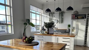 A kitchen with a wooden table, white cabinets, and a refrigerator.