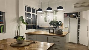 A modern kitchen with white cabinets, a wooden countertop, and pendant lighting.