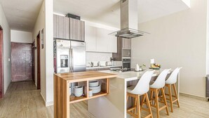 Una cocina moderna con una isla central, electrodomésticos de acero inoxidable y una zona de comedor con taburetes de bar.