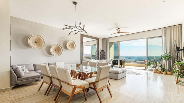 Amplia sala de estar con comedor, ventanas grandes con vistas y ventilador de techo.