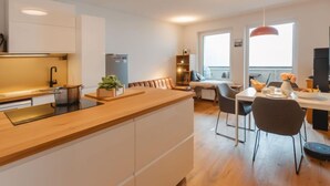 A modern kitchen with white cabinets, a wooden countertop, and a dining area with a table and chairs.