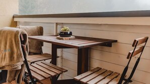 A wooden table with a vase of flowers, two chairs, and a bench.