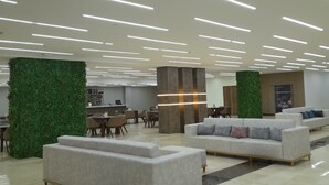 Un vestíbulo amplio con iluminación moderna, paredes decorativas verdes y cómodas zonas de estar.