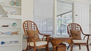 A room with wicker chairs, a small table, and a shelf with decorative items. - Coastal Chic House in Cocoa Beach w/Private Yard - Walk to Beach, Pier & Ron-Jon (Cocoa Beach)