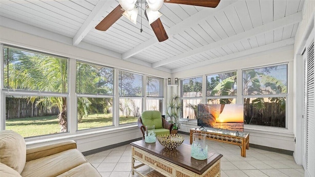 A sunroom with large windows, a ceiling fan, a green chair, and a coffee table with decorative items. - Coastal Chic House in Cocoa Beach w/Private Yard - Walk to Beach, Pier & Ron-Jon (Cocoa Beach)