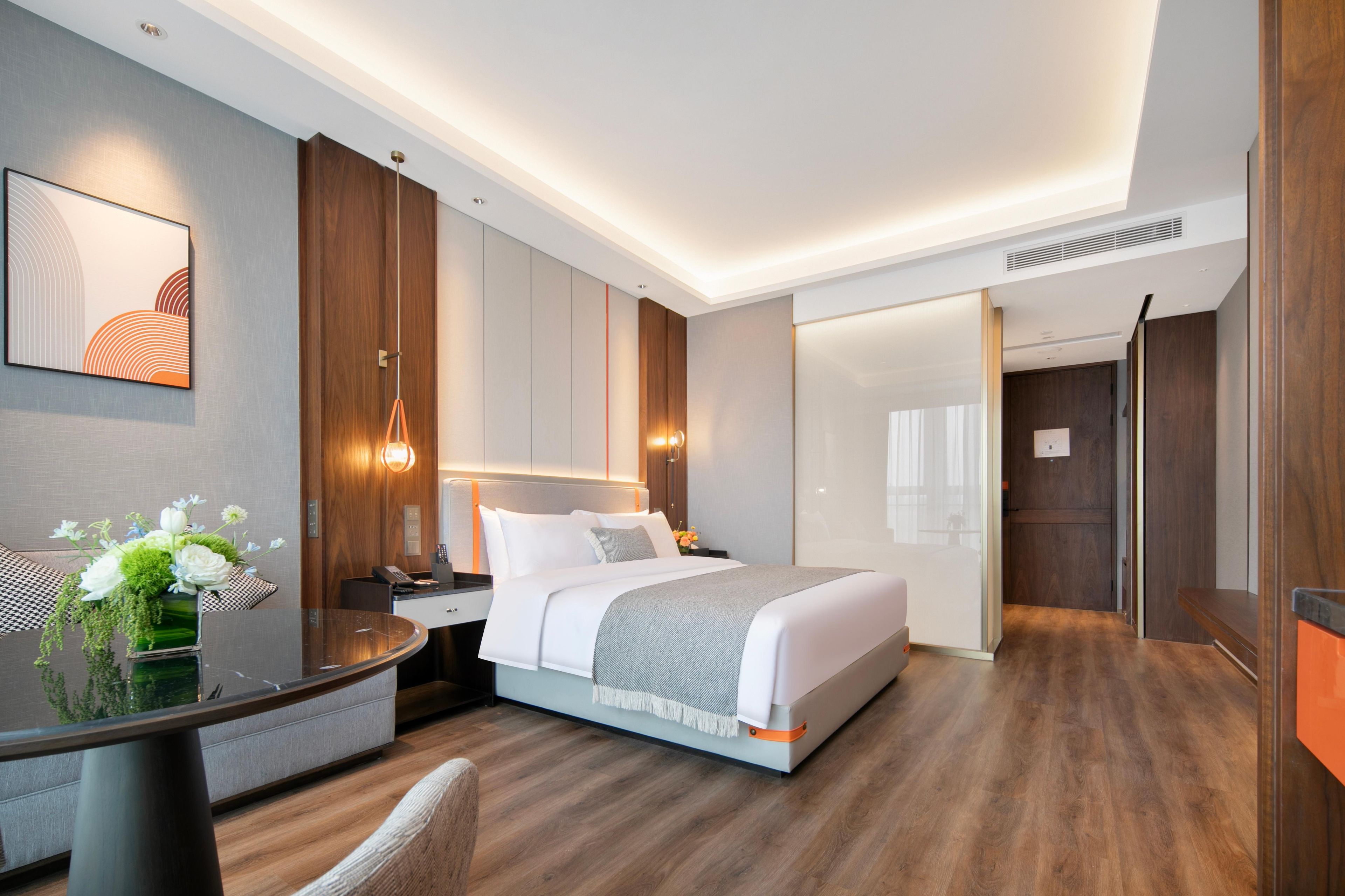 A modern hotel room with a large bed, bedside tables, a desk, and a chair.