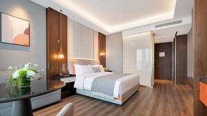 Een moderne hotelkamer met een groot bed, nachtkastjes, een bureau en een stoel.