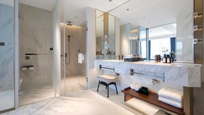 Een moderne badkamer met een douchecabine van glas, een grote spiegel en een wastafel met een marmeren aanrechtblad.