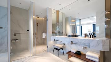 A modern bathroom with a glass-enclosed shower, a large mirror, and a vanity with a marble countertop.