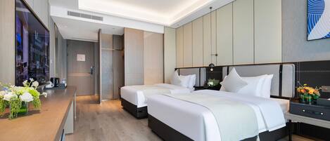 Una habitación de hotel moderna con dos camas, un escritorio de madera con un florero y un ventanal grande.