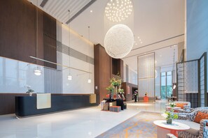 Een moderne lobby met een receptiebalie, een zithoek en grote ramen.