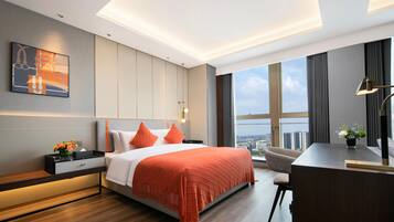 Quarto de hotel moderno com uma cama grande, uma escrivaninha e vista para a cidade.