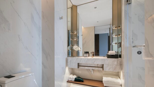 Een moderne badkamer met een marmeren vloer, een grote spiegel, een wastafelmeubel en een douchecabine met glazen wanden.