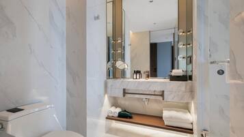 A modern bathroom with a marble floor, a large mirror, a vanity with a sink, and a glass shower enclosure.