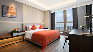 Een moderne hotelkamer met een groot bed, een bureau en uitzicht op de stad.