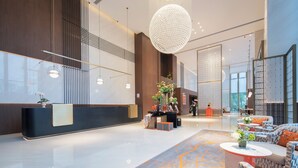 Een moderne lobby met een receptiebalie, zithoek en decoratieve verlichting.