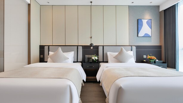 Une chambre d’hôtel moderne avec deux lits, une table de chevet avec une lampe et une œuvre d’art accrochée au mur.