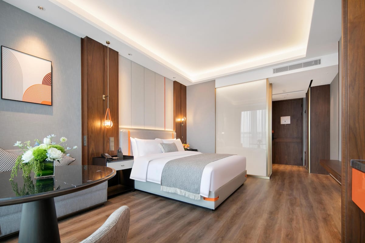 A modern hotel room with a large bed, bedside tables, a desk, and a chair.