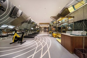 Un gimnasio moderno con equipo de ejercicio, una recepción y un muro de espejos.