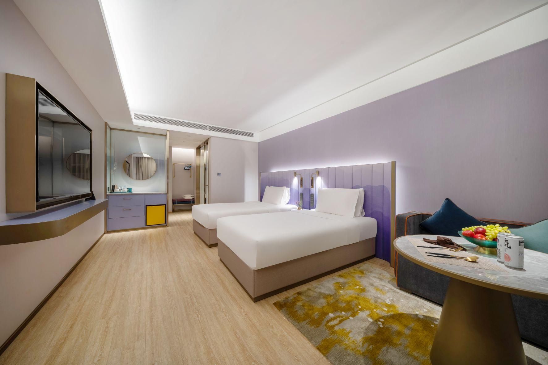 A hotel room with two beds, a sitting area with a table, and a large mirror.