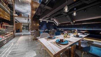 A modern restaurant with a long dining table, chairs, and a variety of dishes.