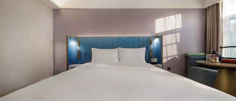 Una habitación de hotel con una cama grande, cabecera con iluminación integrada, mesita de noche y una ventana con cortinas.