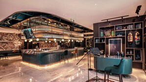 Zona de bar moderna con techo curvo, barra de varios niveles y diferentes opciones de asientos, incluyendo taburetes y sillas.