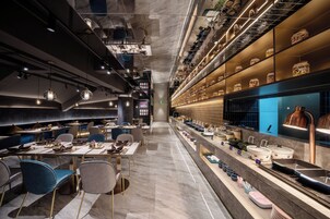 Un interior de restaurante moderno con una barra alargada, zona de estar e iluminación decorativa.