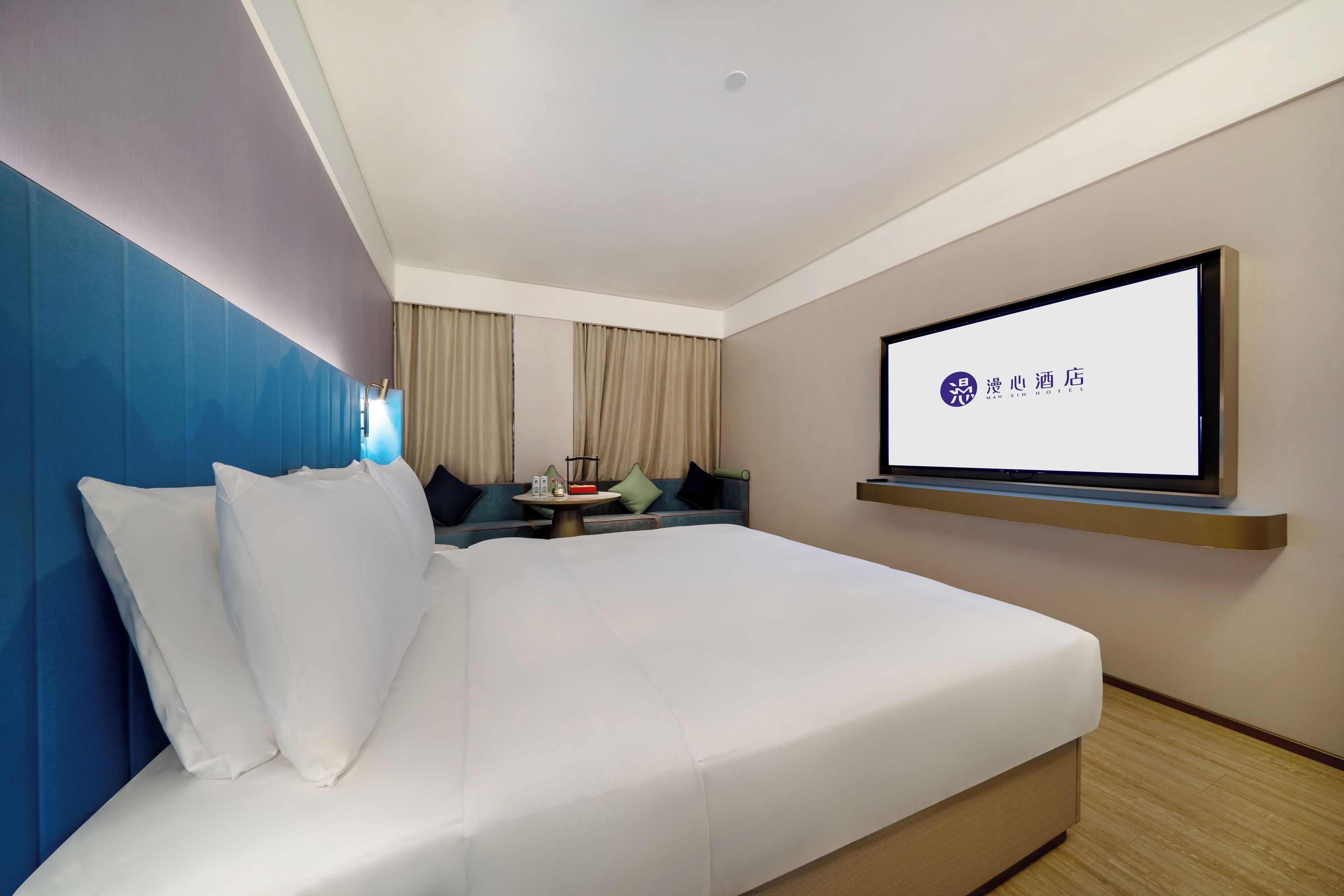 Een hotelkamer met een bed, een aan de muur bevestigde televisie en een klein tafeltje met een afstandsbediening.