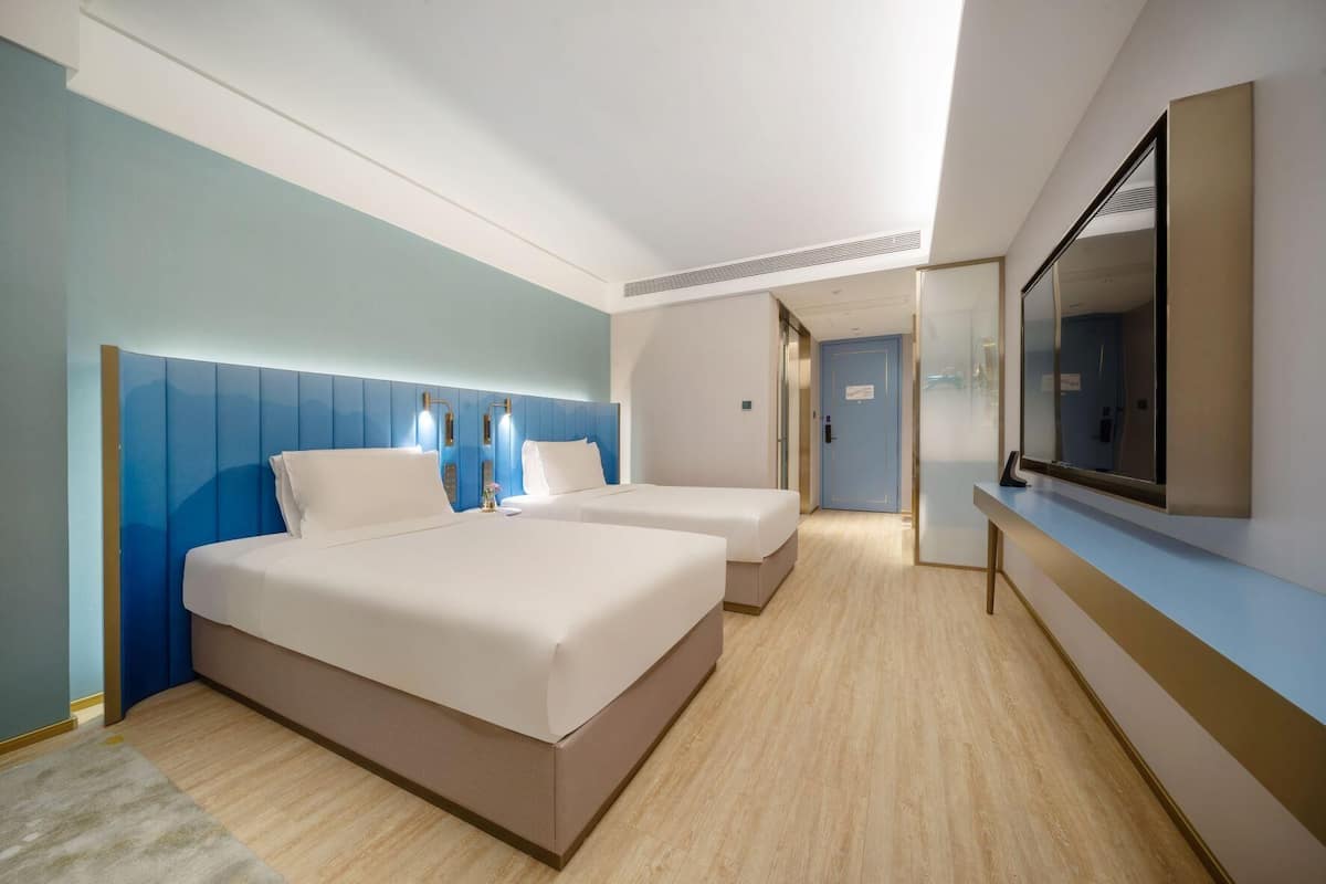 A hotel room with two beds, a large mirror, and a door leading to a bathroom.