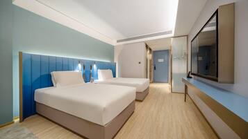 A hotel room with two beds, a large mirror, and a door leading to a bathroom.