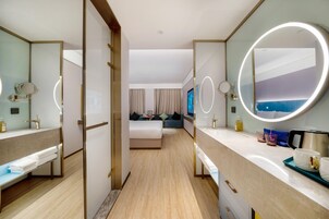 Una habitación de hotel con cama, zona de estar, baño con espejo y televisión.