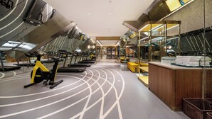 A modern gym with exercise equipment, a reception desk, and a mirror wall. - Manxin Hotel Hefei Jingkai District Pearl Plaza (Hefei)