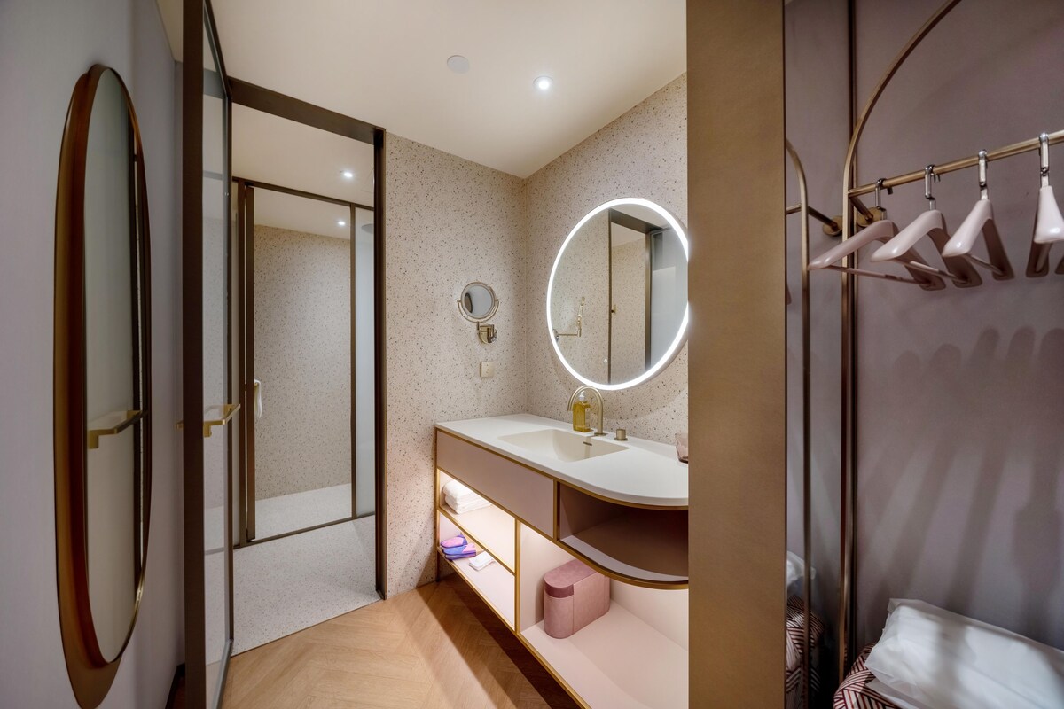 Un baño moderno con tocador, espejo y perchero.