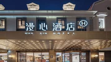 The exterior of the Man Xin Hotel with illuminated signage and a modern entrance.