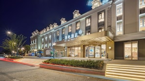 Un hotel de estilo arquitectónico europeo clásico, con una entrada imponente que incluye un dosel y señalización iluminada.