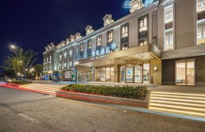 Un hotel de estilo arquitectónico europeo clásico, con una entrada imponente que incluye un dosel y señalización iluminada.