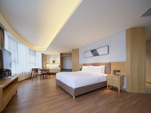 A modern hotel room with a large bed, a desk, and a chair. There is a small kitchenette in the corner. - Madison Hotel Xianyang Zhuquan Road Wanda Plaza (Xianyang)