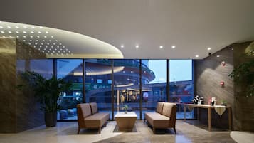 A modern lobby with two sofas, a coffee table, and a reception desk.