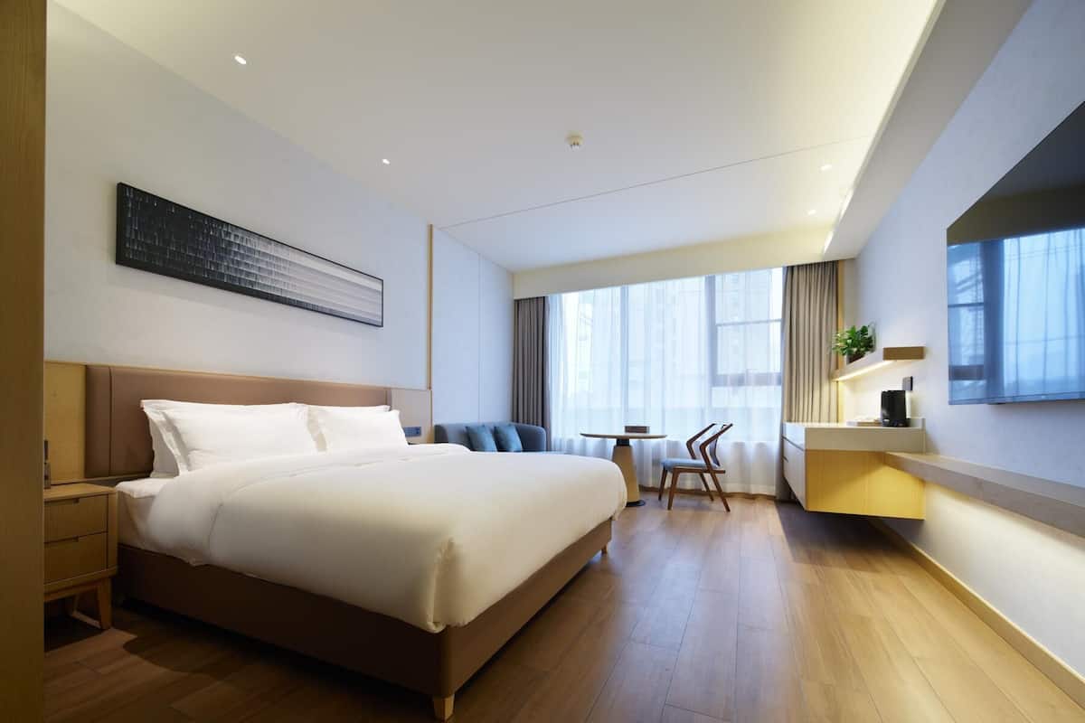 Ein modernes Hotelzimmer mit einem großen Bett, einem Schreibtisch und einem Stuhl.
